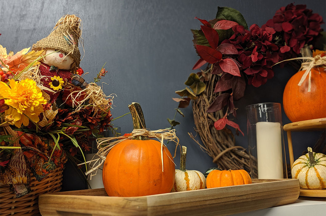 Teak Serving Tray with Rounded Sides from Lipper International with three pumpkins on it, surrounded by Fall foliage, a Fall wreath, and a candle